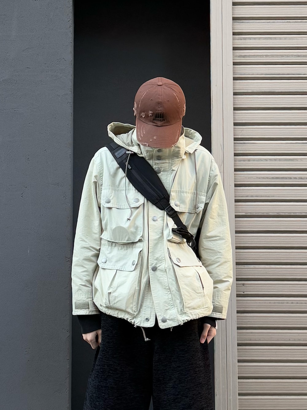 ブラック系のショルダーバッグ、ブラック系のスニーカー、ベージュ系のマウンテンパーカーを着用したメンズの冬コーディネートの4枚目の写真