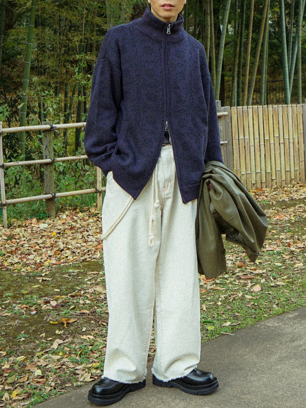 パープル系のニット/セーター、ブラック系のデニムパンツ、ブラック系のカバーオールを着用したメンズの冬コーディネートの4枚目の写真