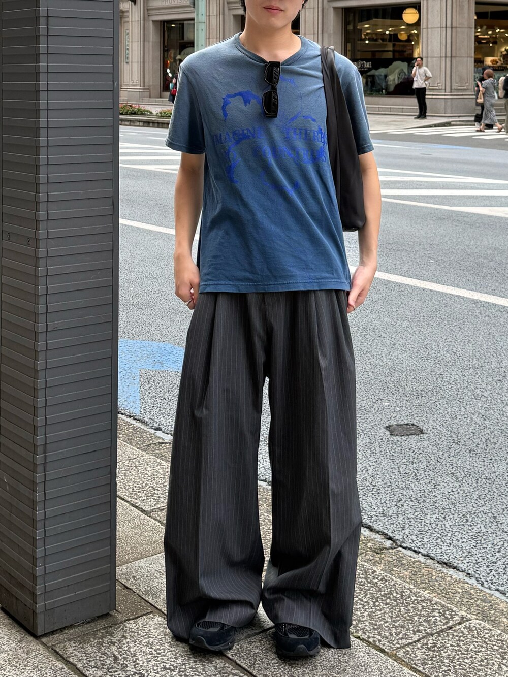 ブルー系のTシャツ/カットソー、グレー系のハンドバッグ、グレー系のスラックスを着用したメンズの夏コーディネートの2枚目の写真