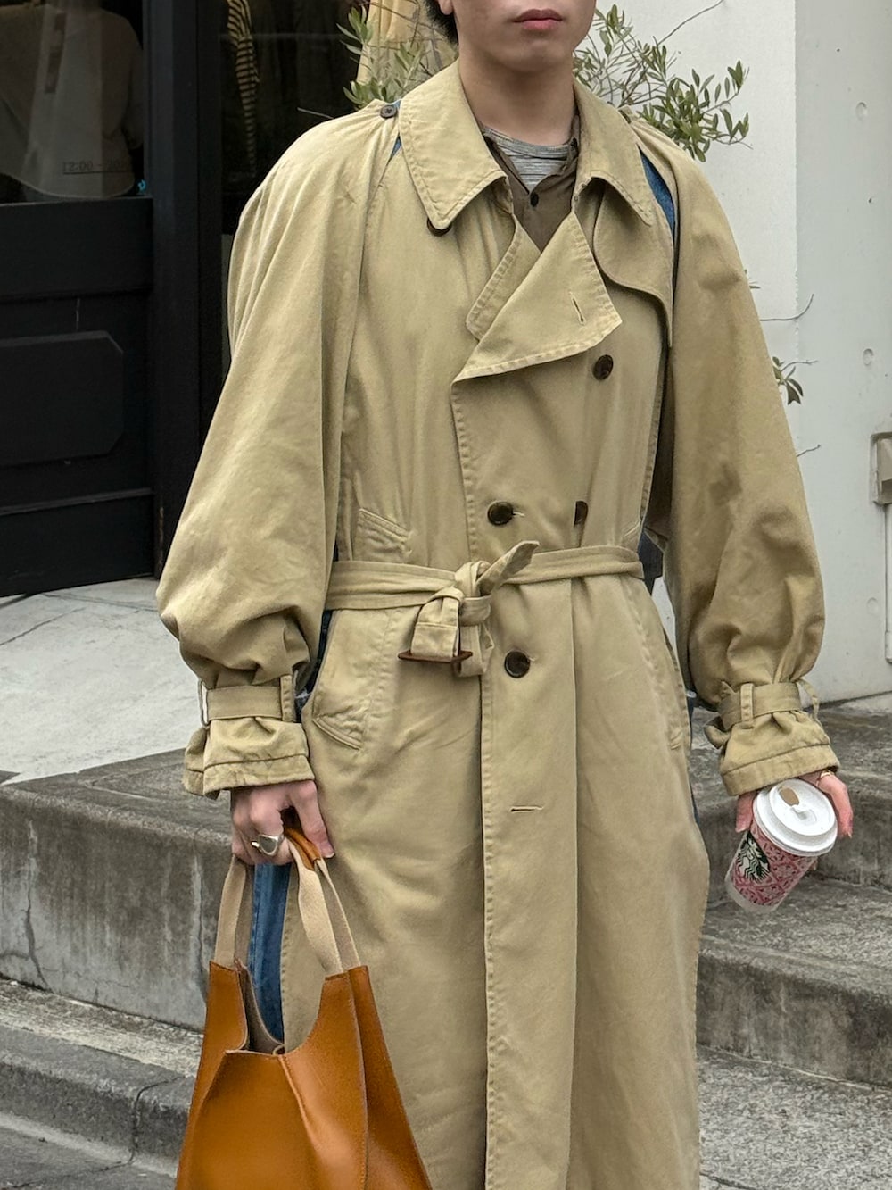 ベージュ系のトレンチコート、グリーン系のシャツ/ブラウス、グレー系のTシャツ/カットソーを着用したメンズの春コーディネートの4枚目の写真