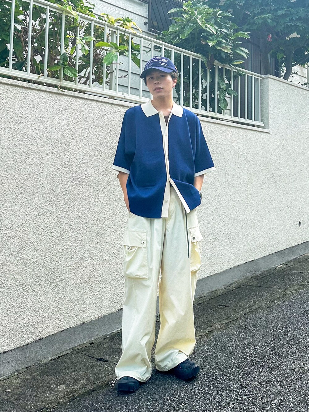 ブルー系のポロシャツ、ホワイト系のカーゴパンツ、ブラック系のスニーカーを着用したメンズの秋コーディネートの3枚目の写真