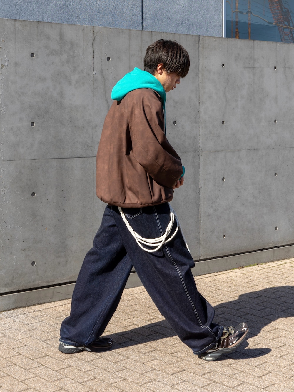 ブラウン系のブルゾン、ブルー系のパーカー、ブルー系のデニムパンツを着用したメンズの秋コーディネートの2枚目の写真