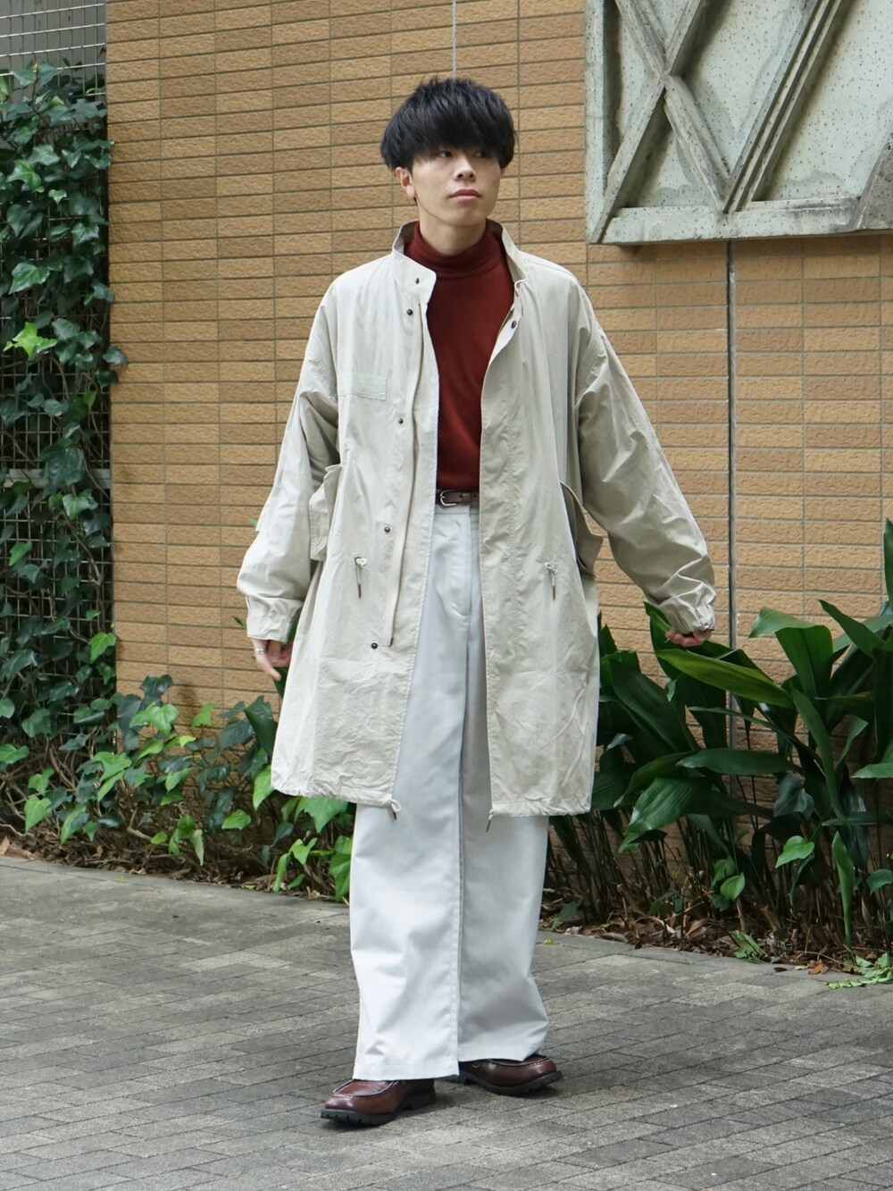 ベージュ系のモッズコート、レッド系のTシャツ/カットソー、ホワイト系のチノパンツを着用したメンズの秋コーディネートの2枚目の写真