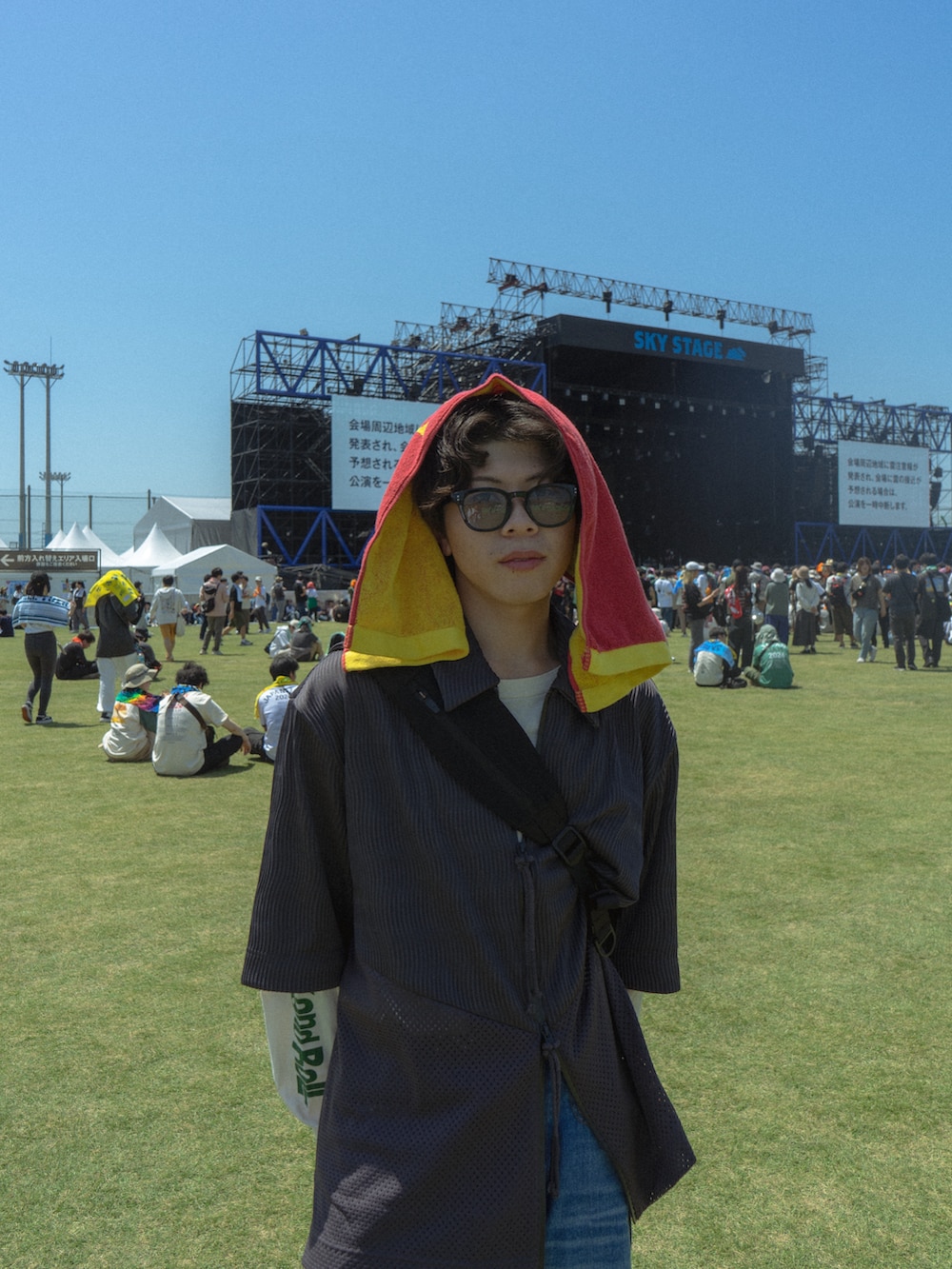 グレー系のトップス、ブラック系のショルダーバッグ、ブルー系のデニムパンツを着用したメンズの春コーディネートの3枚目の写真