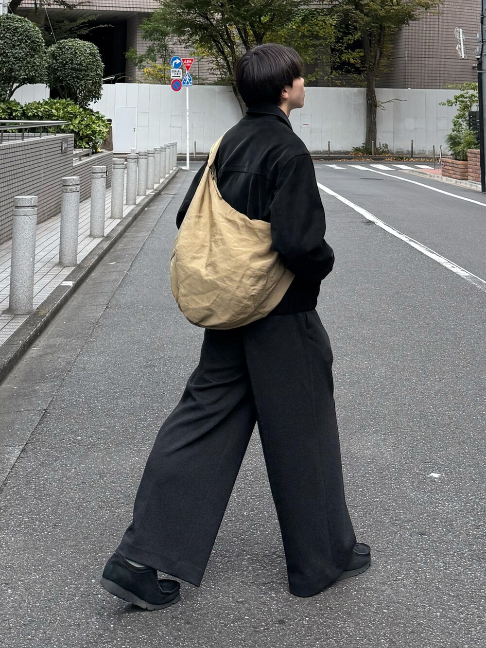 ブラック系のブルゾン、グレー系のスラックス、ベージュ系のショルダーバッグを着用したメンズの冬コーディネートの3枚目の写真