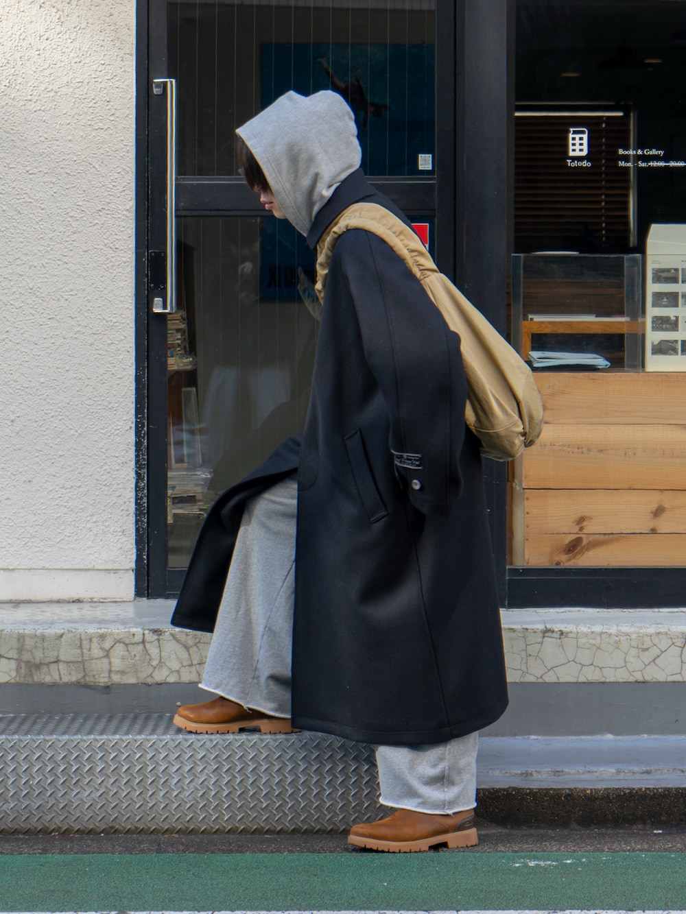 ブラック系のステンカラーコート、グレー系のスウェットパンツ、ベージュ系のショルダーバッグを着用したメンズの冬コーディネートの2枚目の写真