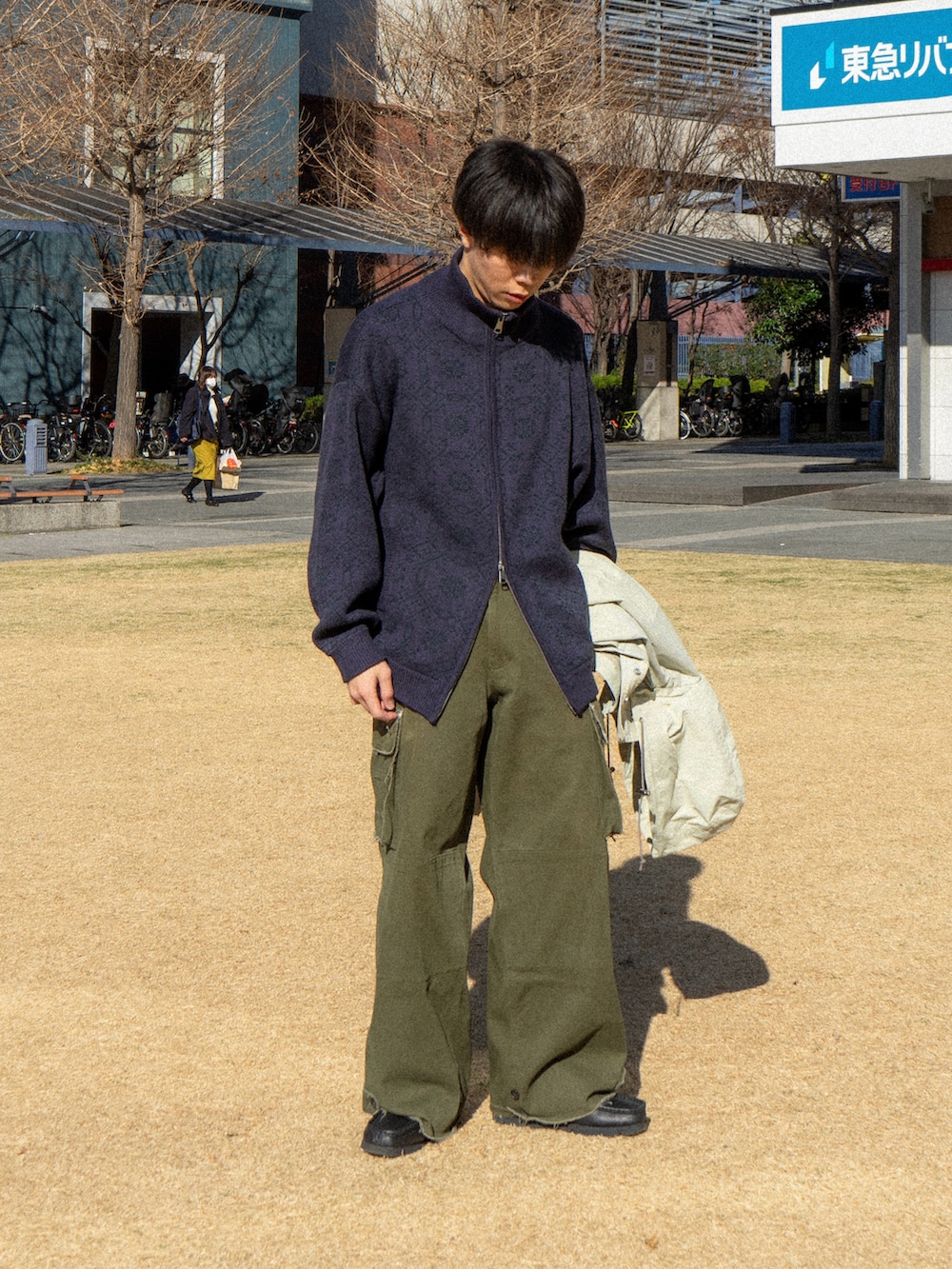 パープル系のニット/セーター、ベージュ系のマウンテンパーカー、グリーン系のカーゴパンツを着用したメンズの冬コーディネートの2枚目の写真