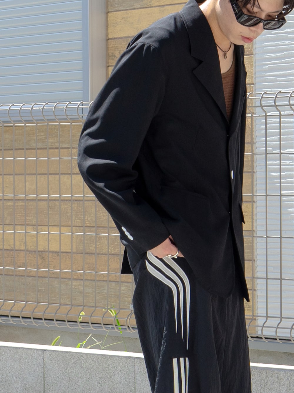 ブラック系のテーラードジャケット、ブラウン系のタンクトップ、ブラック系のスウェットパンツを着用したメンズの秋コーディネートの4枚目の写真