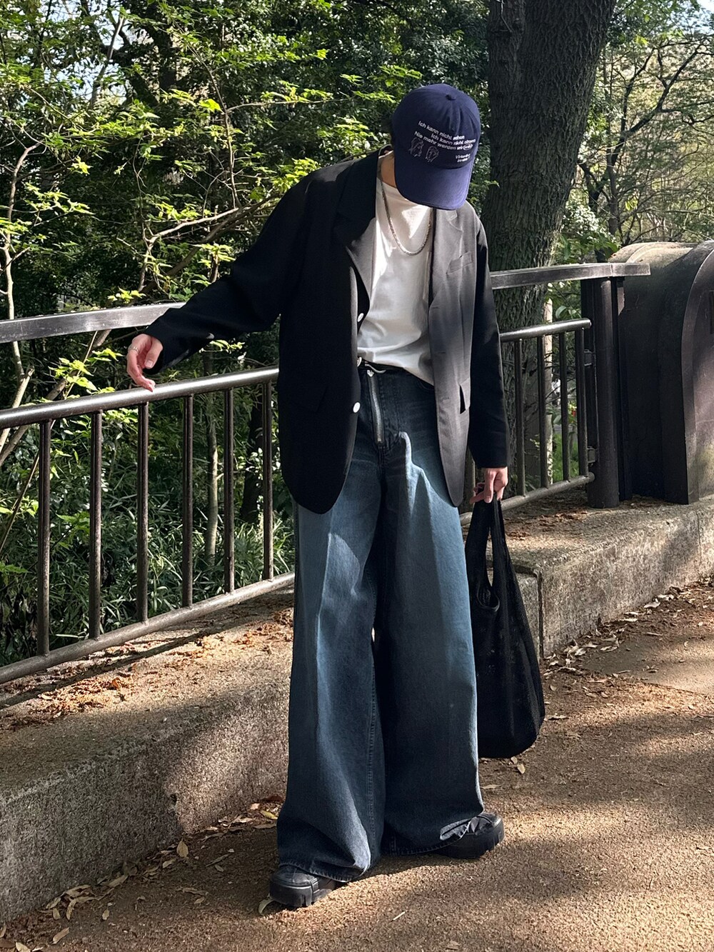 ブラック系のテーラードジャケット、ブルー系のデニムパンツ、ブラック系のショルダーバッグを着用したメンズの春コーディネートの5枚目の写真