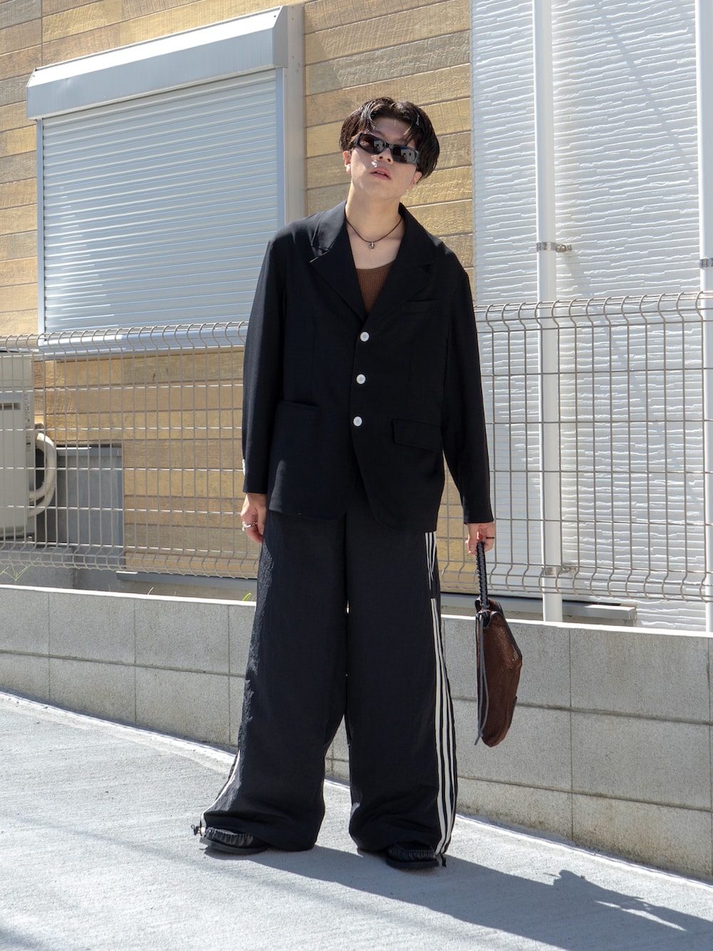 ブラック系のテーラードジャケット、ブラウン系のタンクトップ、ブラック系のスウェットパンツを着用したメンズの秋コーディネートの2枚目の写真