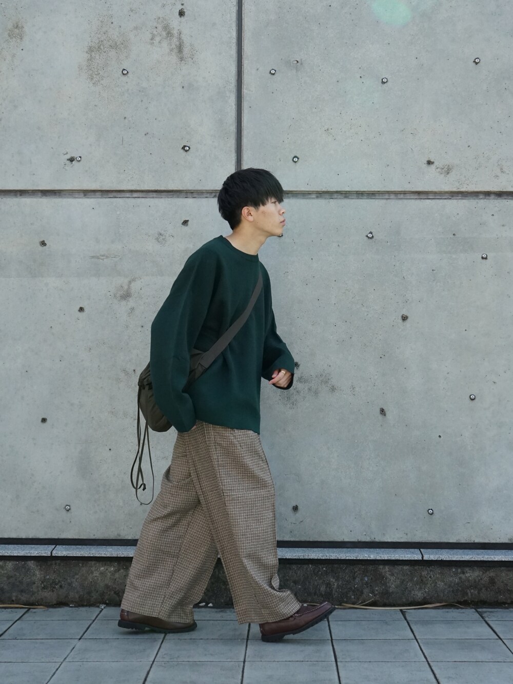 グリーン系のニット/セーター、ベージュ系のスラックス、ブラウン系のモカシン/デッキシューズを着用したメンズの秋コーディネートの4枚目の写真