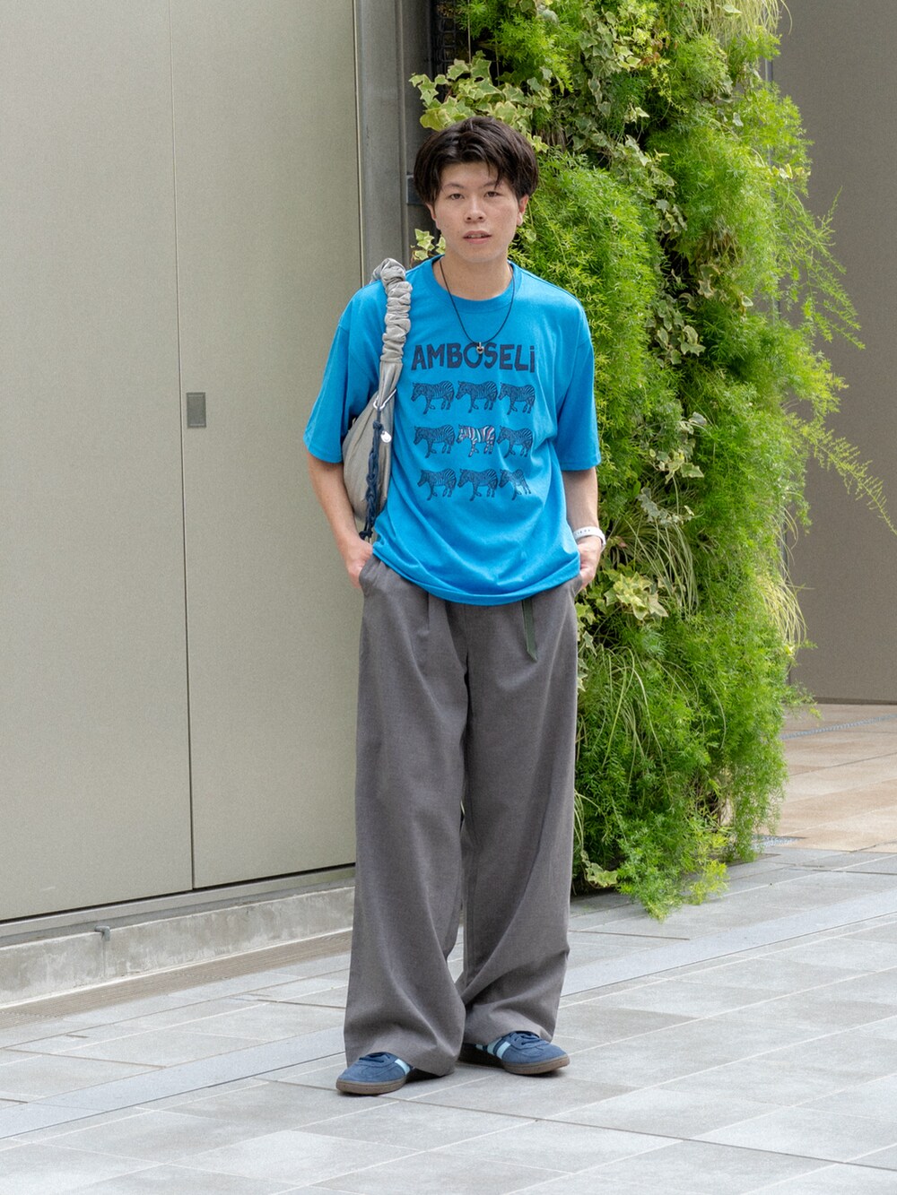 ブルー系のTシャツ/カットソー、グレー系のスラックス、ブルー系のスニーカーを着用したメンズの夏コーディネートの2枚目の写真