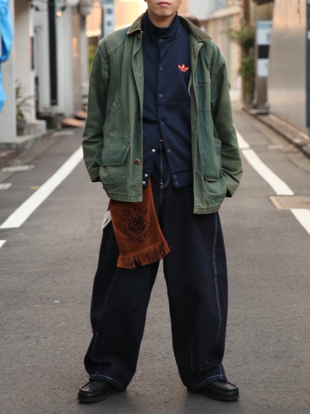 グリーン系のカバーオール、ブルー系のジャージ、ブルー系のデニムパンツを着用したメンズの冬コーディネートの5枚目の写真