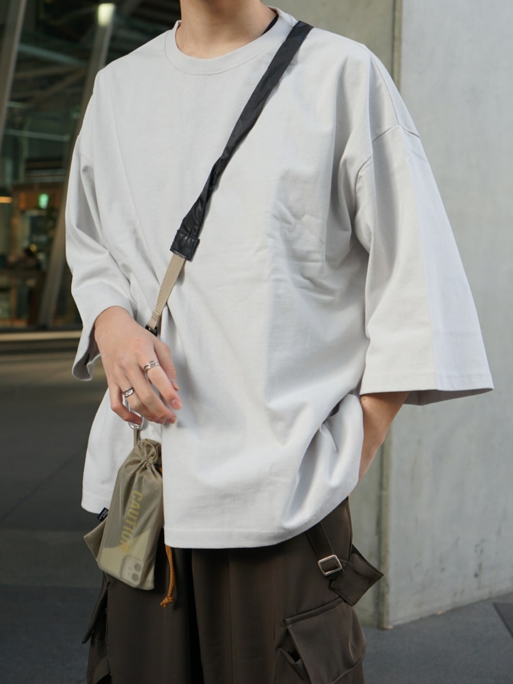 グレー系のTシャツ/カットソー、グリーン系のサロペット/オーバーオール、ベージュ系のショルダーバッグを着用したメンズの冬コーディネートの4枚目の写真