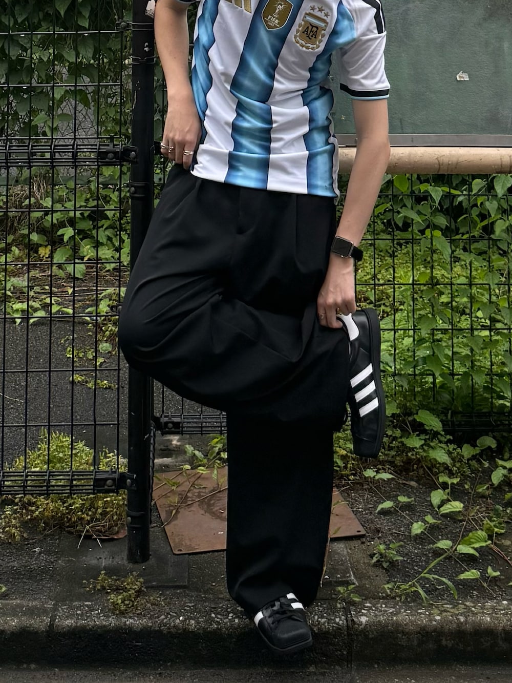ホワイト系のTシャツ/カットソー、ブラック系のスラックス、ブラック系のスニーカーを着用したメンズの夏コーディネートの2枚目の写真