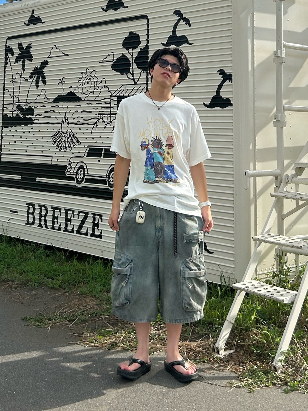 ホワイト系のTシャツ/カットソー、ブルー系のデニムパンツ、ブラック系のサンダルを着用したメンズの夏コーディネートの2枚目の写真