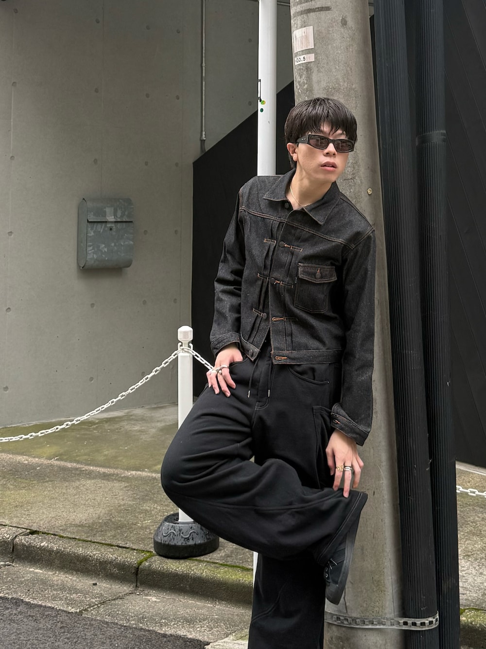 ブラック系のデニムジャケット、ブラック系のスウェットパンツ、ブラック系のスニーカーを着用したメンズの秋コーディネートの2枚目の写真