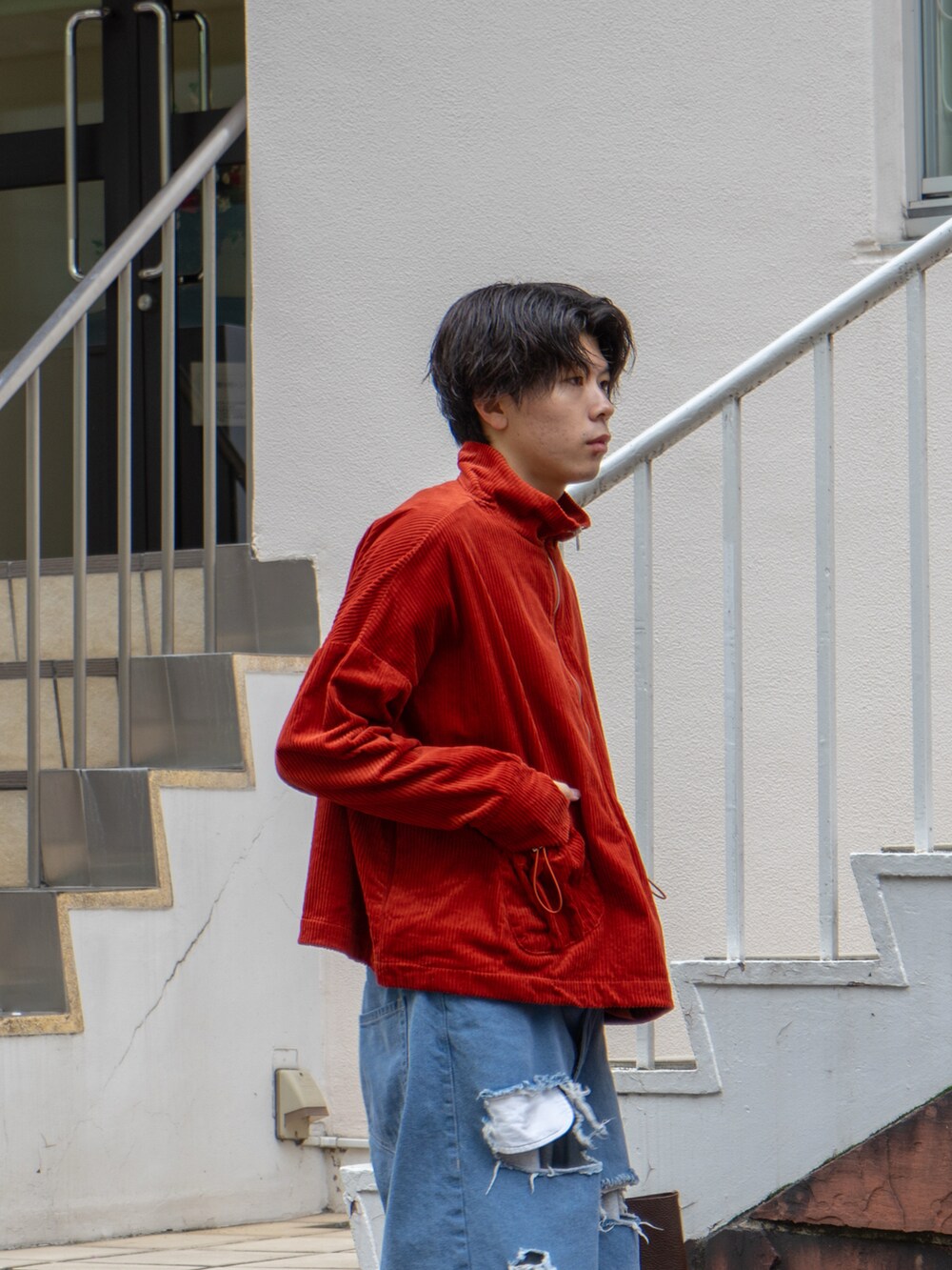 オレンジ系のブルゾン、グレー系のスウェットパンツ、ブラウン系のハンドバッグを着用したメンズの秋コーディネートの4枚目の写真