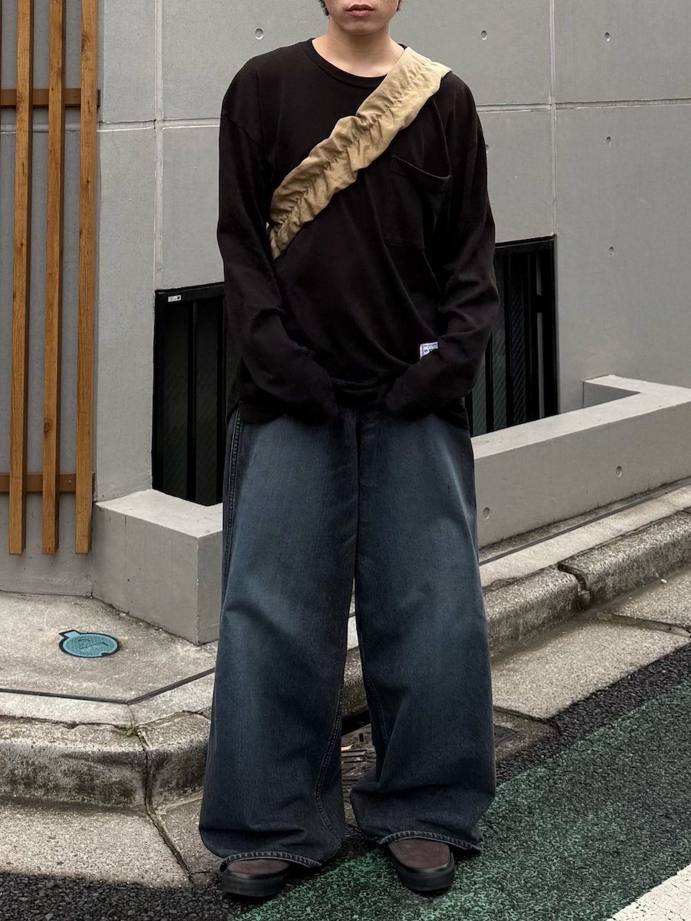 ブラック系のTシャツ/カットソー、ブルー系のデニムパンツ、ベージュ系のショルダーバッグを着用したメンズの春コーディネートの2枚目の写真