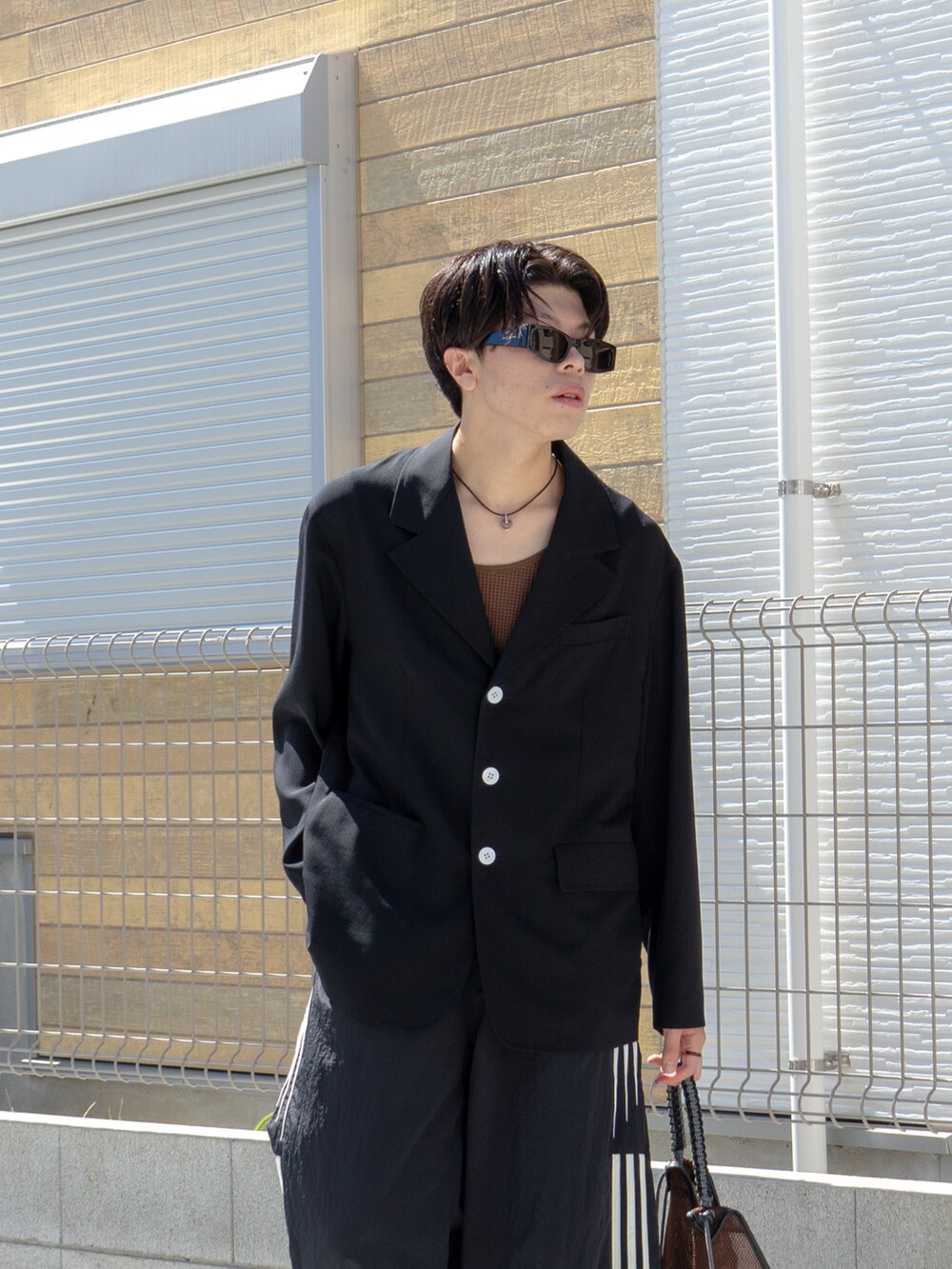 ブラック系のテーラードジャケット、ブラウン系のタンクトップ、ブラック系のスウェットパンツを着用したメンズの秋コーディネートの5枚目の写真