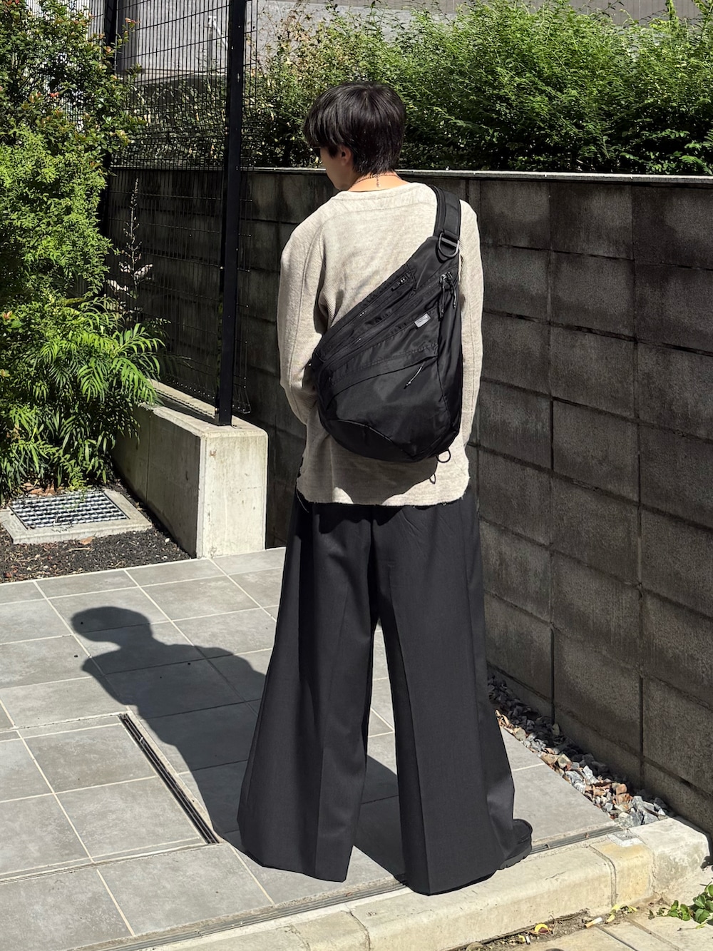 グレー系のTシャツ/カットソー、ブラック系のショルダーバッグ、グレー系のスラックスを着用したメンズの秋コーディネートの2枚目の写真