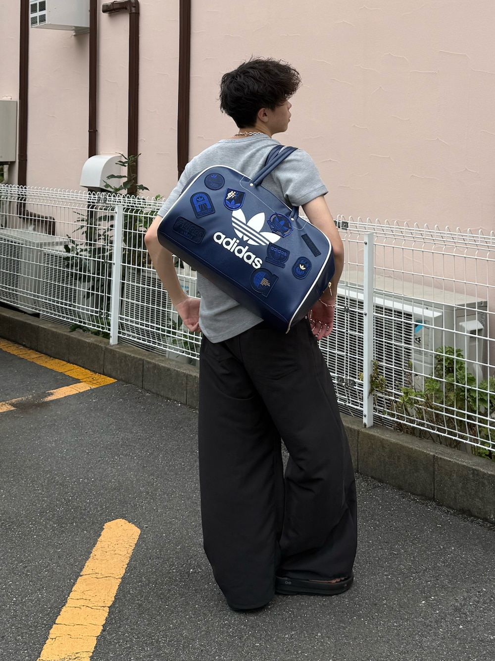 グレー系のTシャツ/カットソー、グレー系のスラックス、ブルー系のボストンバッグを着用したメンズの夏コーディネートの2枚目の写真