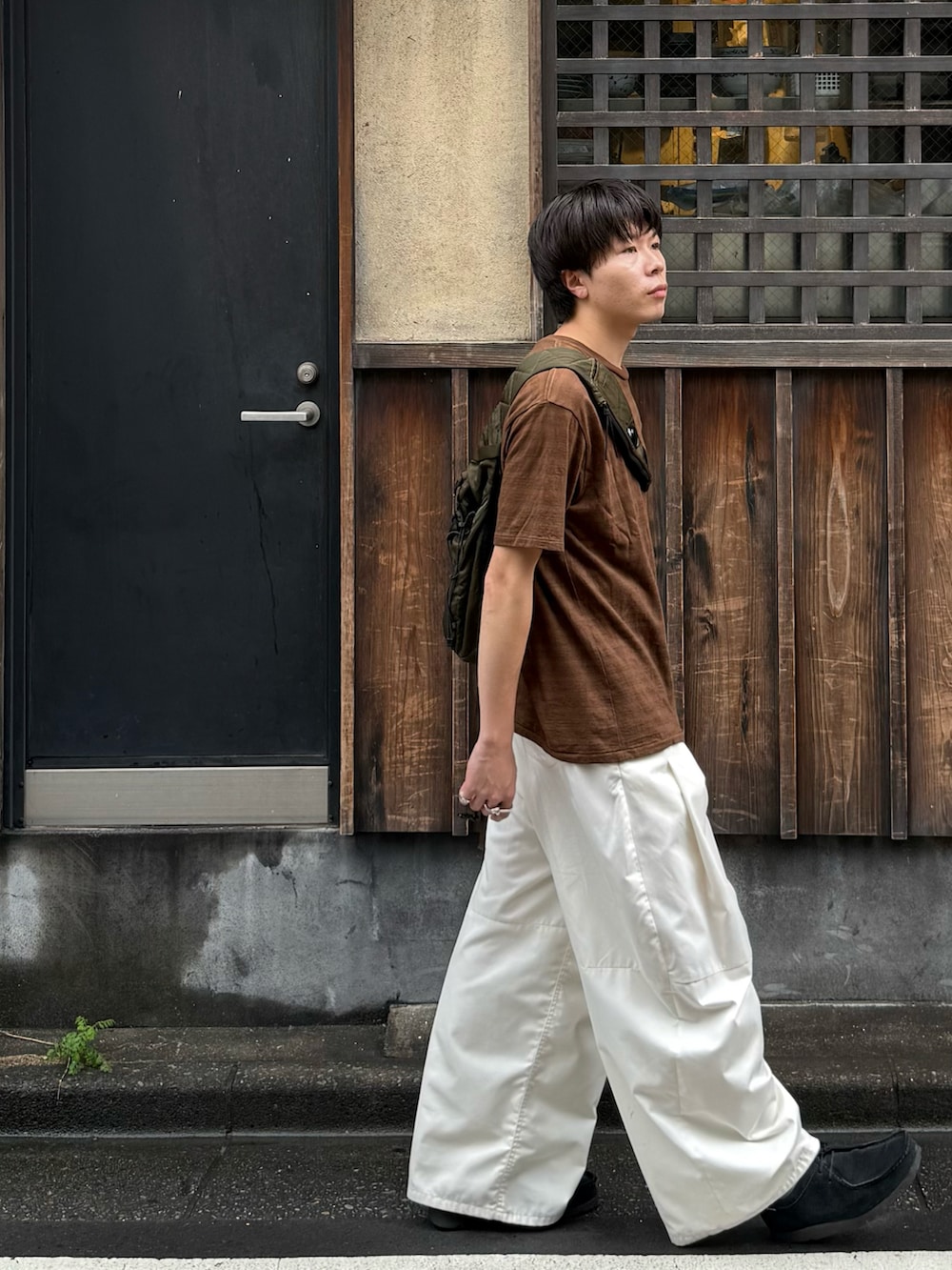 ブラウン系のTシャツ/カットソー、グリーン系のバックパック/リュック、ホワイト系のその他パンツを着用したメンズの秋コーディネートの2枚目の写真