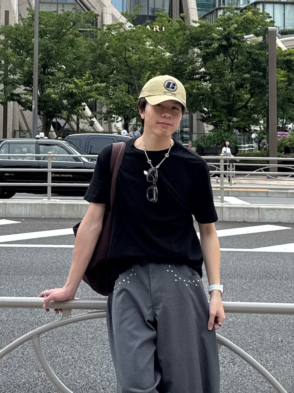 ブラック系のTシャツ/カットソー、グレー系のスラックス、ブラウン系のトートバッグを着用したメンズの夏コーディネートの3枚目の写真