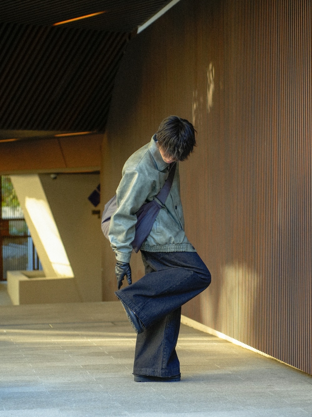 グレー系のブルゾン、ブラック系のデニムパンツ、グレー系のショルダーバッグを着用したメンズの冬コーディネートの3枚目の写真