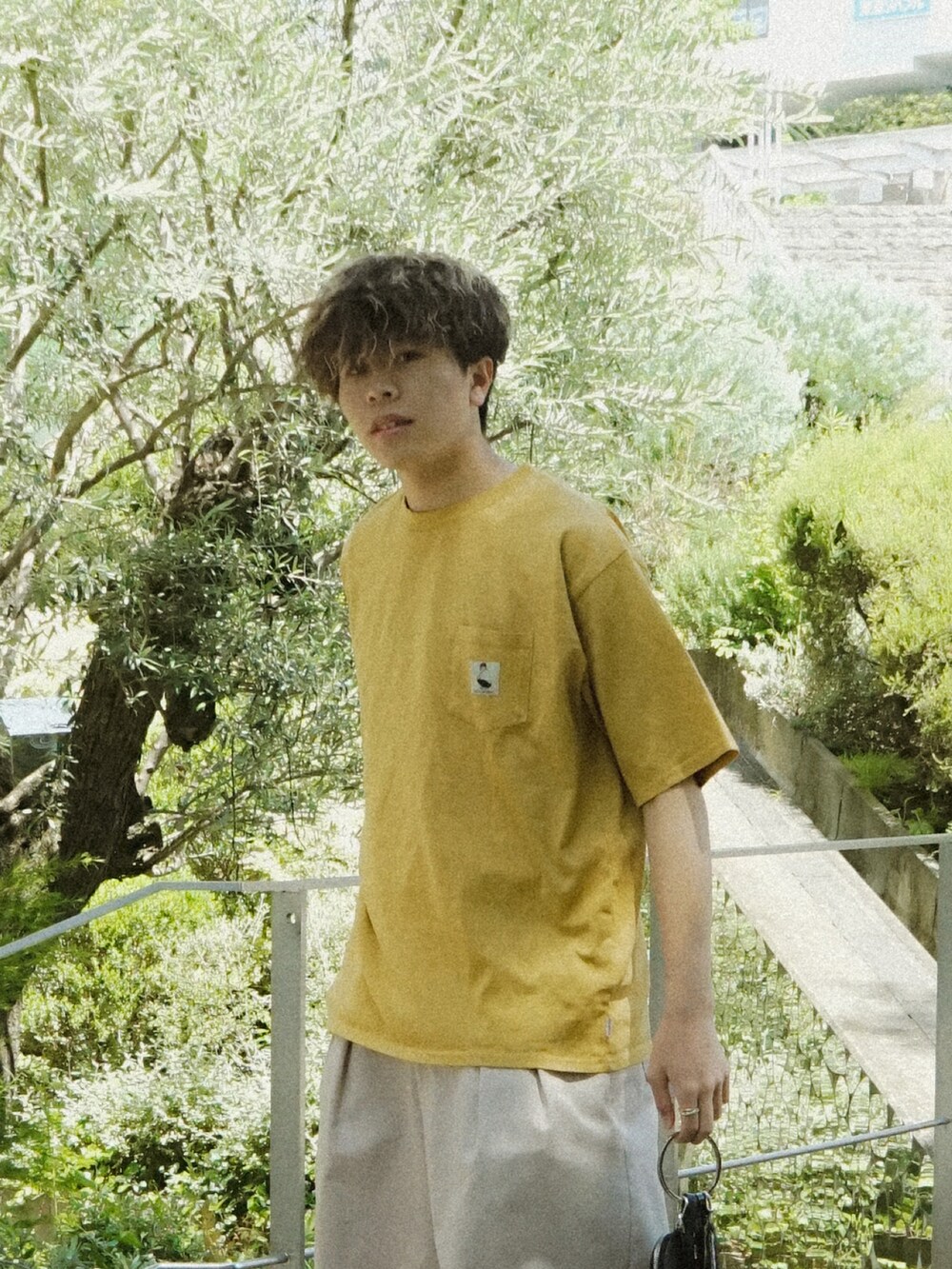 イエロー系のTシャツ/カットソー、ベージュ系のその他パンツ、ブラック系のショルダーバッグを着用したメンズの春コーディネートの3枚目の写真