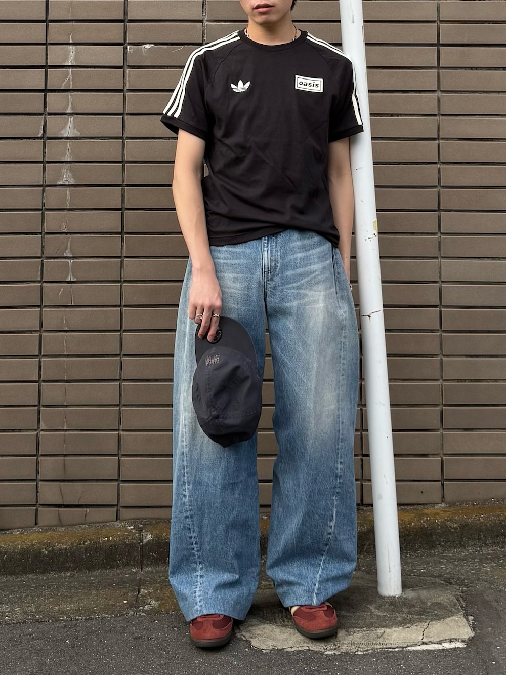 ブラック系のTシャツ/カットソー、ブルー系のデニムパンツ、ブラウン系のスニーカーを着用したメンズの夏コーディネートの4枚目の写真