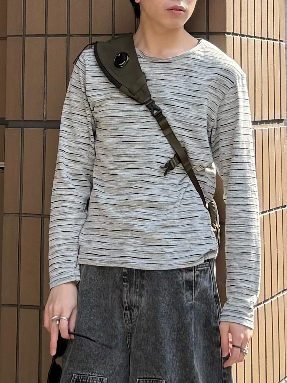 グレー系のTシャツ/カットソー、グレー系のデニムパンツ、グリーン系のバックパック/リュックを着用したメンズの春コーディネートの2枚目の写真