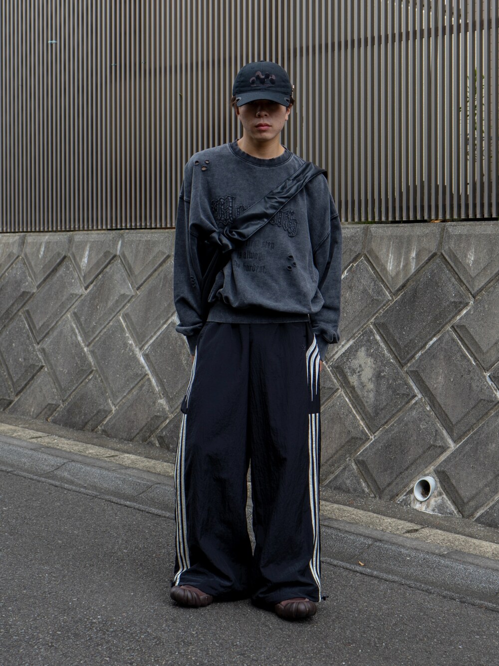 グレー系のスウェット、ブラック系のショルダーバッグ、ブラック系のスウェットパンツを着用したメンズの秋コーディネートの2枚目の写真