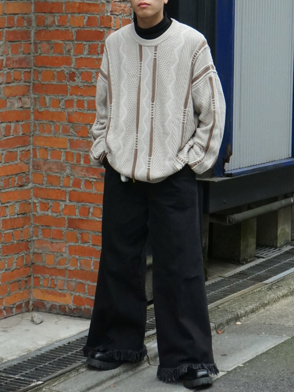 ベージュ系のニット/セーター、ブラック系のTシャツ/カットソー、ブラック系のデニムパンツを着用したメンズの冬コーディネートの4枚目の写真