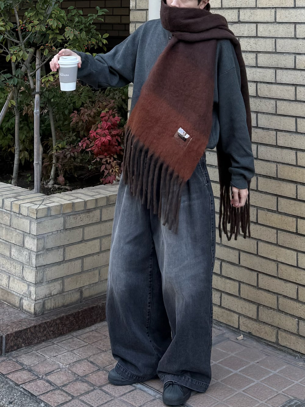 グレー系のニット/セーター、ブラック系のデニムパンツ、ブラック系のスニーカーを着用したメンズの冬コーディネートの3枚目の写真