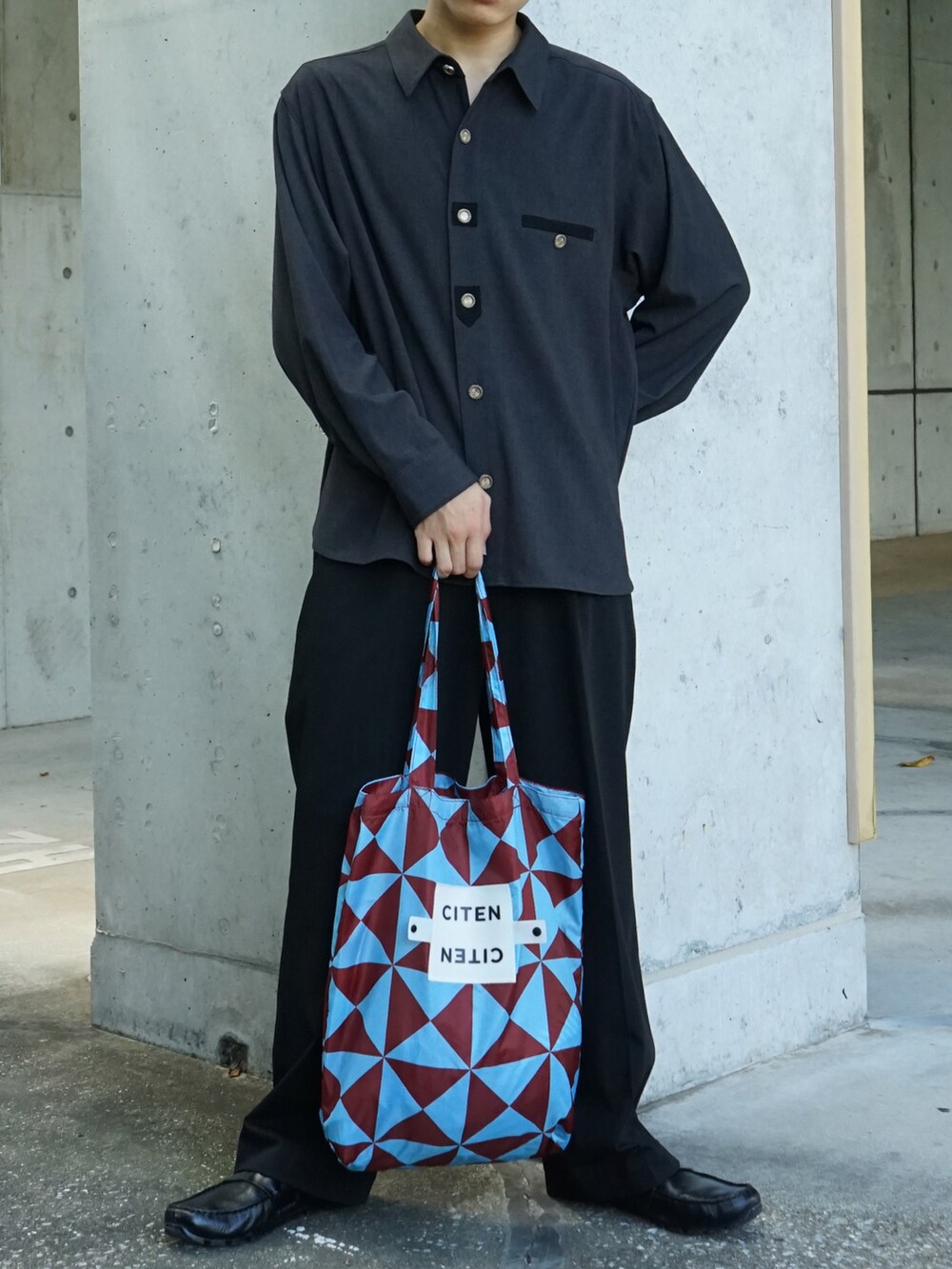 グレー系のシャツ/ブラウス、ブラック系のスラックス、ブルー系のトートバッグを着用したメンズの夏コーディネートの5枚目の写真