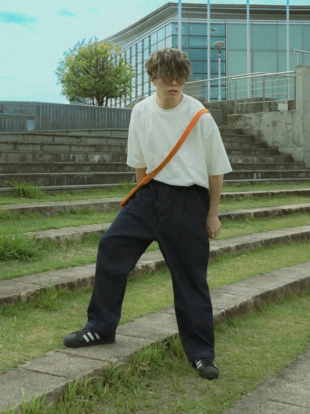 ホワイト系のTシャツ/カットソー、ブルー系のデニムパンツ、オレンジ系のショルダーバッグを着用したメンズの春コーディネートの2枚目の写真