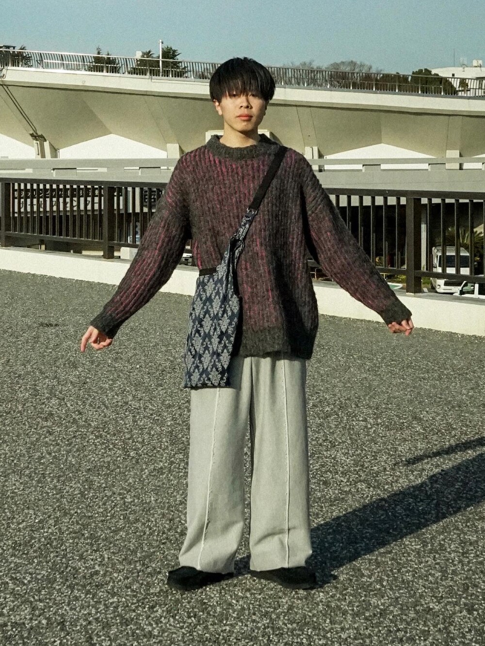 ブラック系のニット/セーター、グレー系のスウェットパンツ、ブルー系のショルダーバッグを着用したメンズの冬コーディネートの2枚目の写真