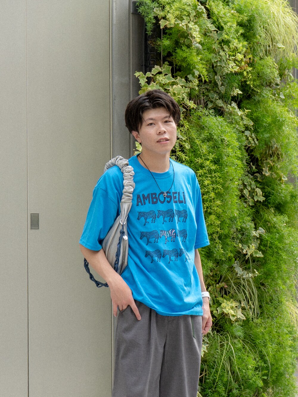 ブルー系のTシャツ/カットソー、グレー系のスラックス、ブルー系のスニーカーを着用したメンズの夏コーディネートの4枚目の写真