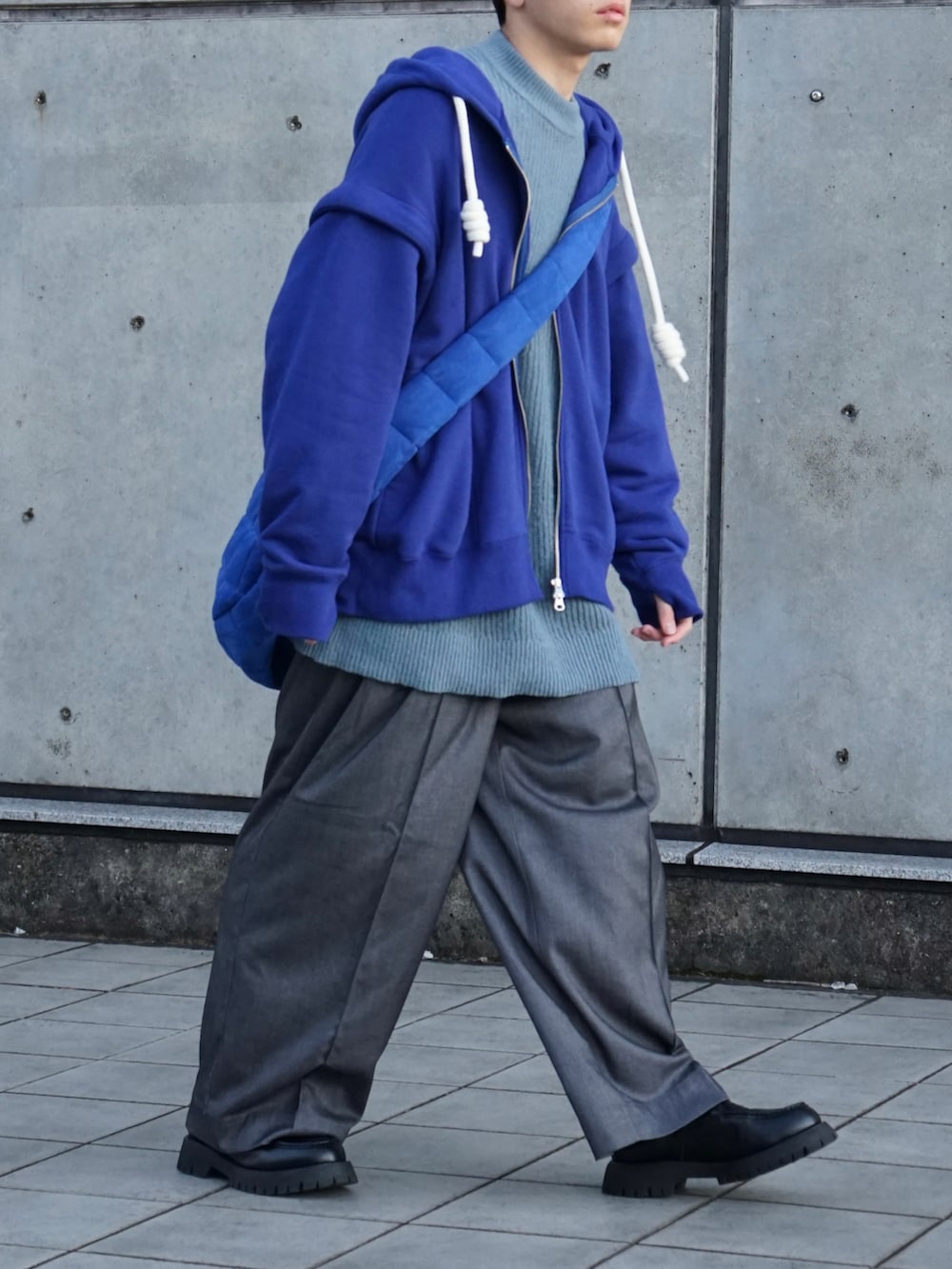 ブルー系のパーカー、ブルー系のニット/セーター、グレー系のスラックスを着用したメンズの秋コーディネートの5枚目の写真