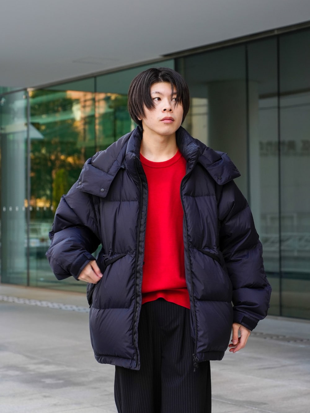 ブラック系のダウンジャケット/コート、レッド系のニット/セーター、ブラック系のスラックスを着用したメンズの冬コーディネートの3枚目の写真