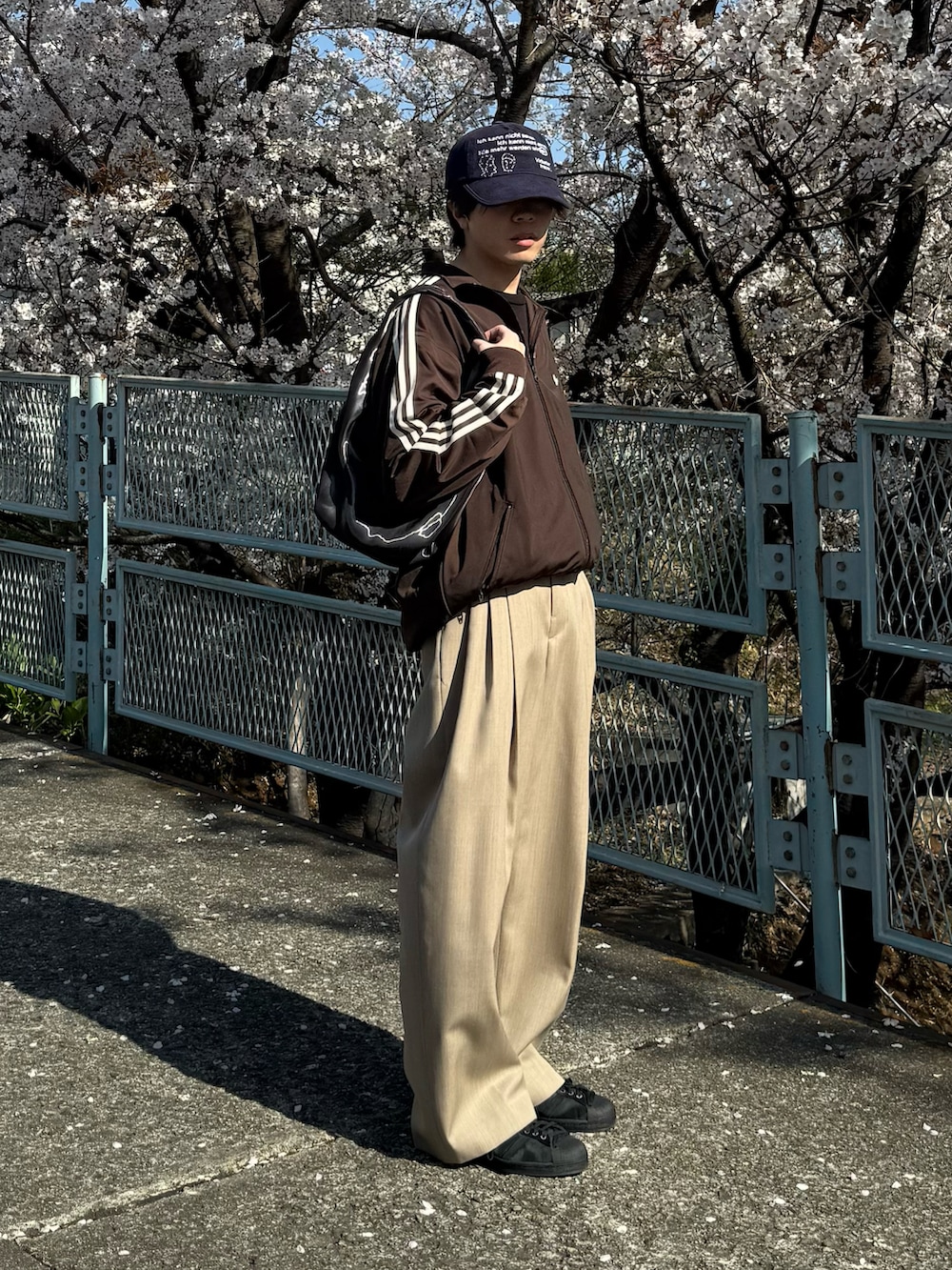 ブラウン系のジャージ、ブラック系のTシャツ/カットソー、ブラック系のスニーカーを着用したメンズの春コーディネートの2枚目の写真