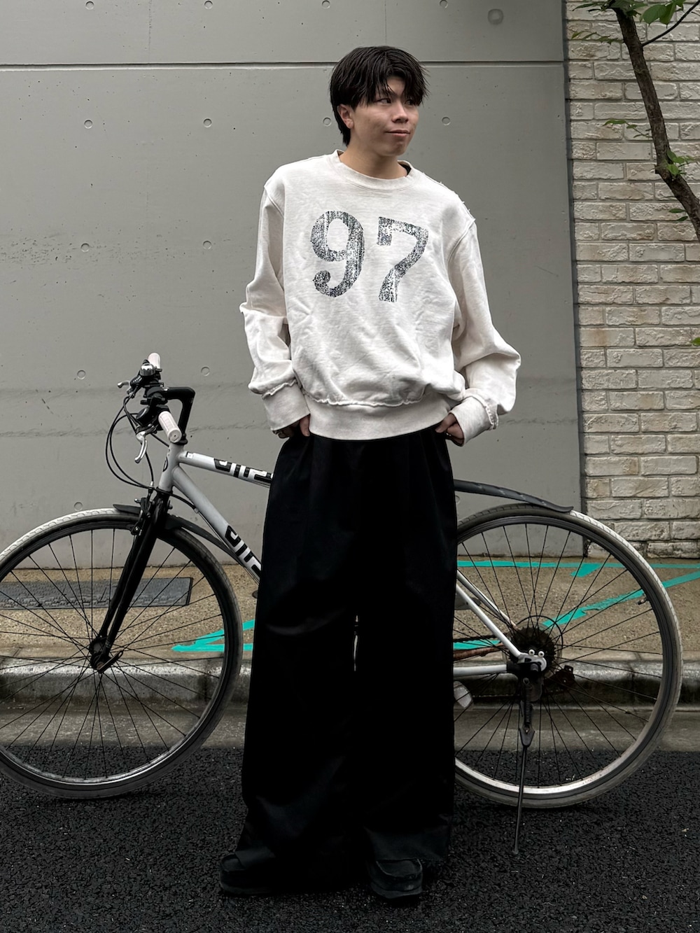 ホワイト系のスウェット、ブラック系のその他パンツ、ブラック系のモカシン/デッキシューズを着用したメンズの春コーディネートの2枚目の写真