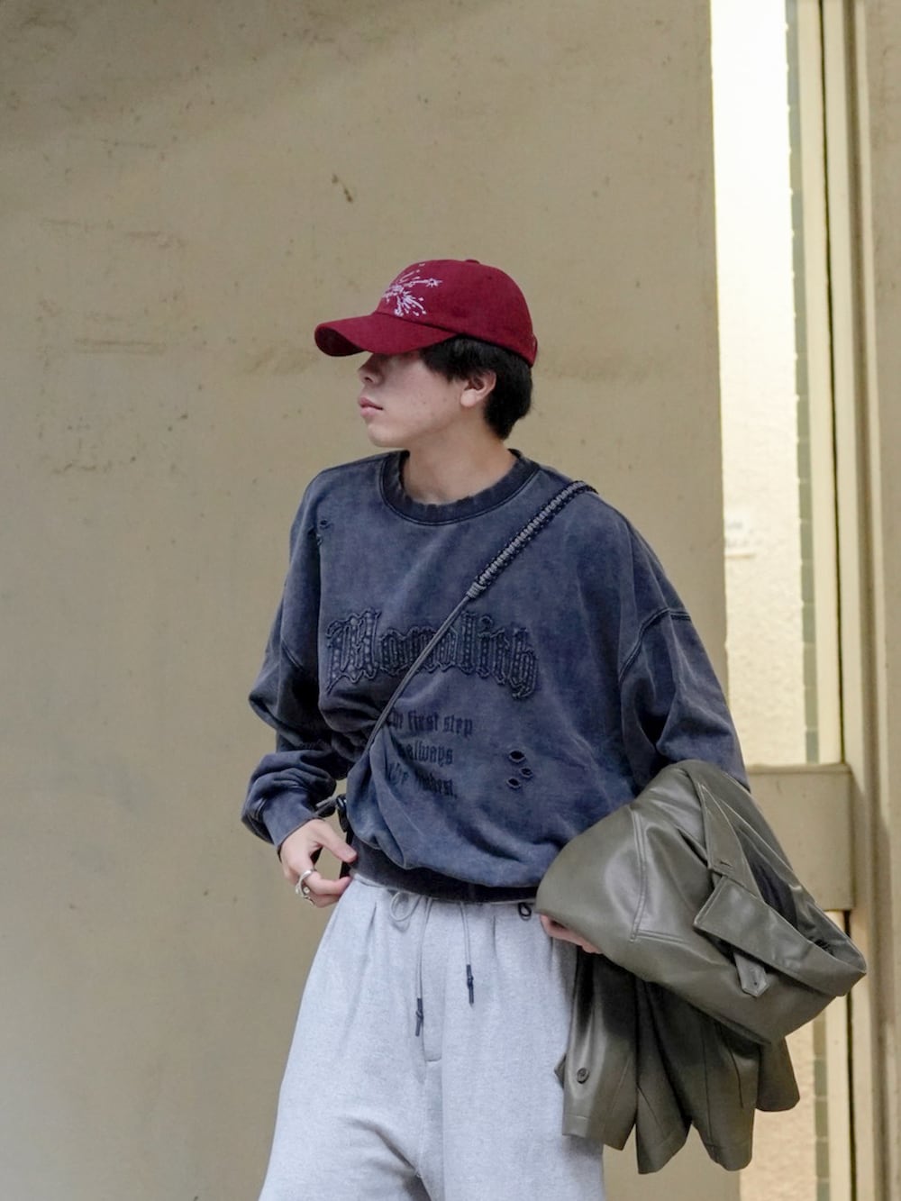 グレー系のスウェット、ブラック系のカバーオール、ブラウン系のショルダーバッグを着用したメンズの秋コーディネートの4枚目の写真