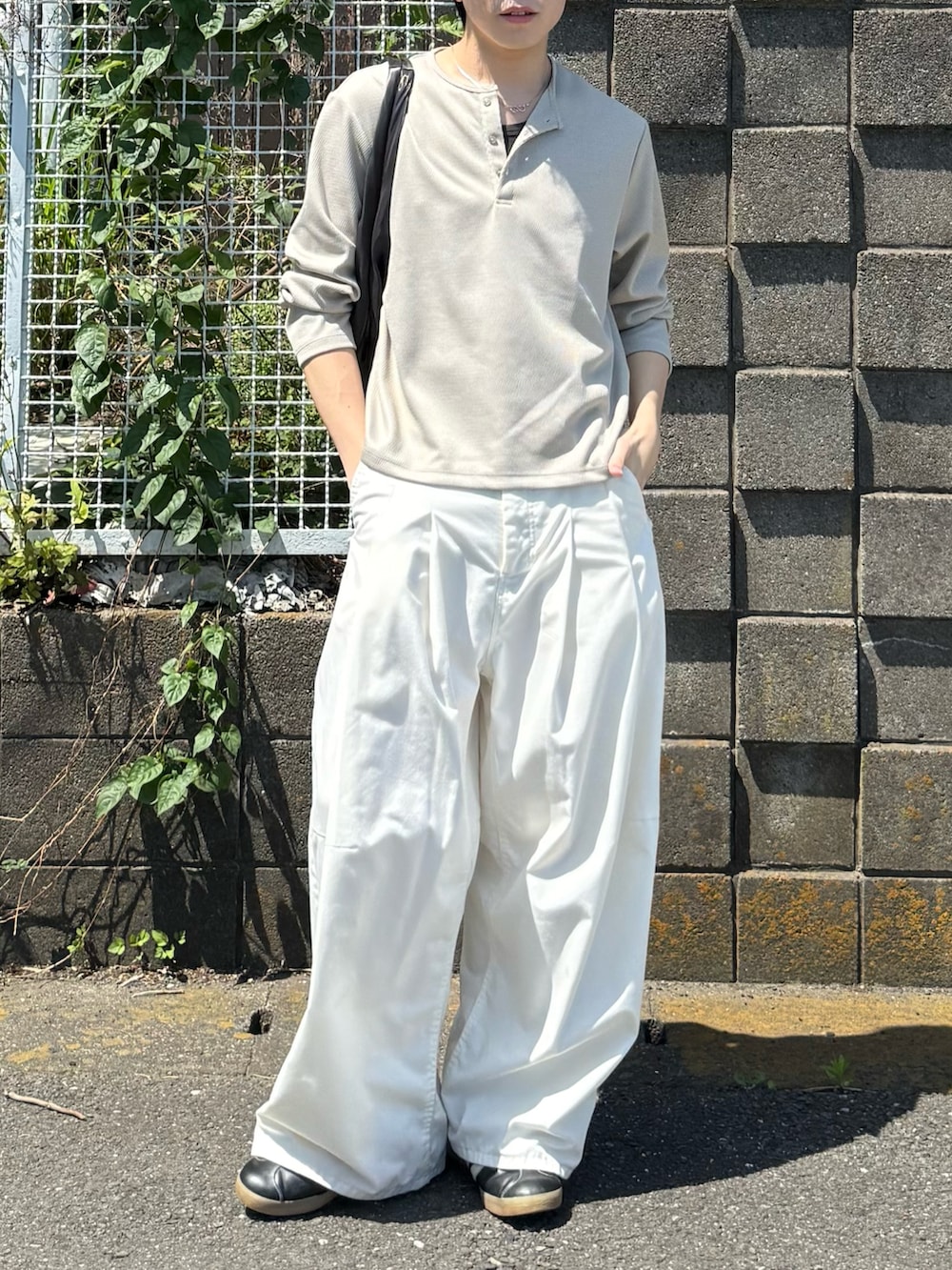 ベージュ系のTシャツ/カットソー、ホワイト系のその他パンツ、グレー系のハンドバッグを着用したメンズの春コーディネートの4枚目の写真