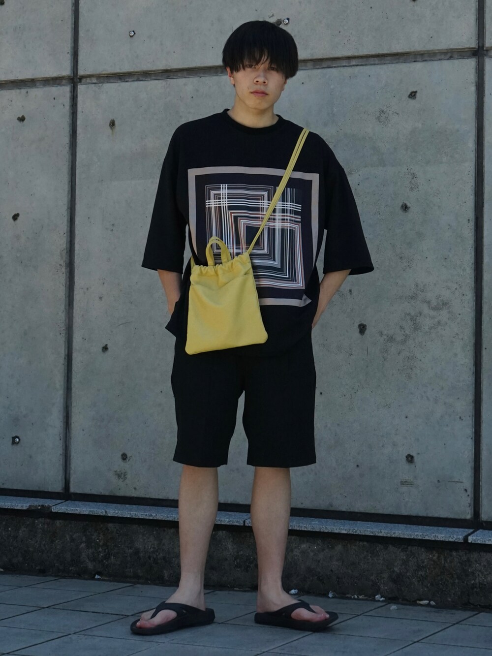 ブラック系のTシャツ/カットソー、ブラック系のスラックス、イエロー系のショルダーバッグを着用したメンズの夏コーディネートの2枚目の写真