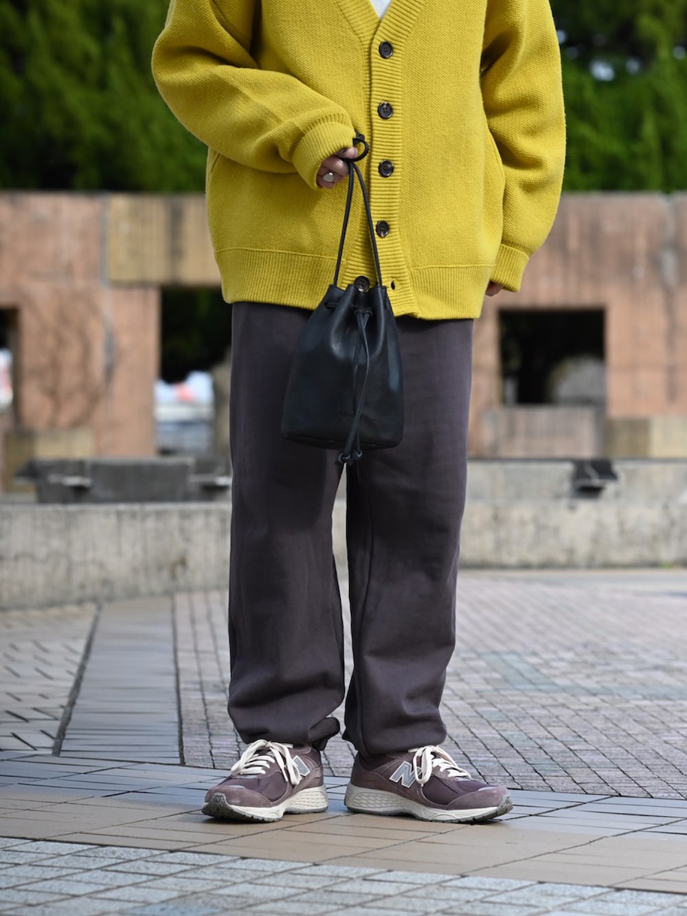 イエロー系のカーディガン/ボレロ、グレー系のスウェットパンツ、ブラック系のショルダーバッグを着用したメンズの春コーディネートの4枚目の写真