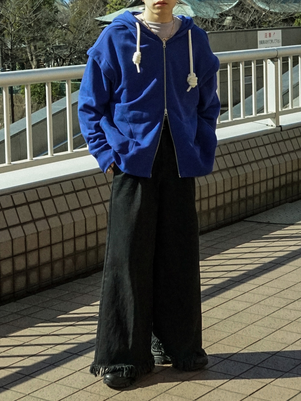 ブルー系のパーカー、ブラック系のデニムパンツ、ブラック系のスニーカーを着用したメンズの春コーディネートの5枚目の写真