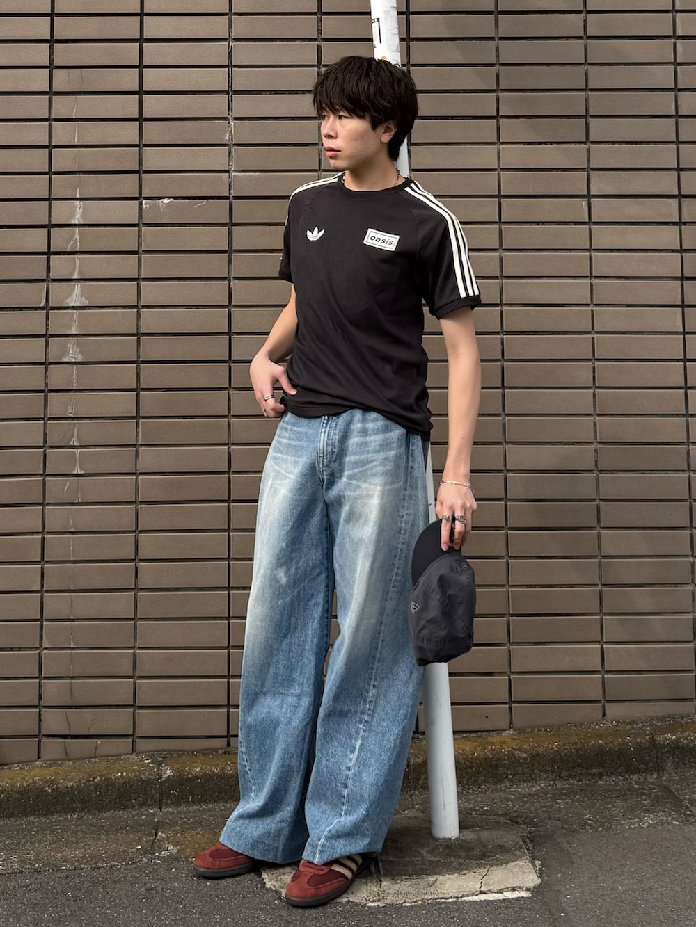 ブラック系のTシャツ/カットソー、ブルー系のデニムパンツ、ブラウン系のスニーカーを着用したメンズの夏コーディネートの2枚目の写真