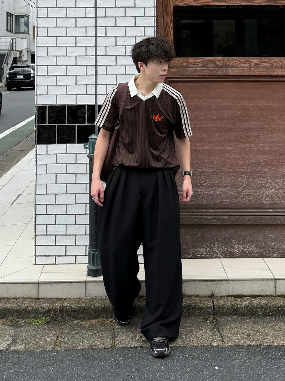 ブラウン系のTシャツ/カットソー、ブラック系のスラックス、ブラウン系のトートバッグを着用したメンズの夏コーディネートの3枚目の写真